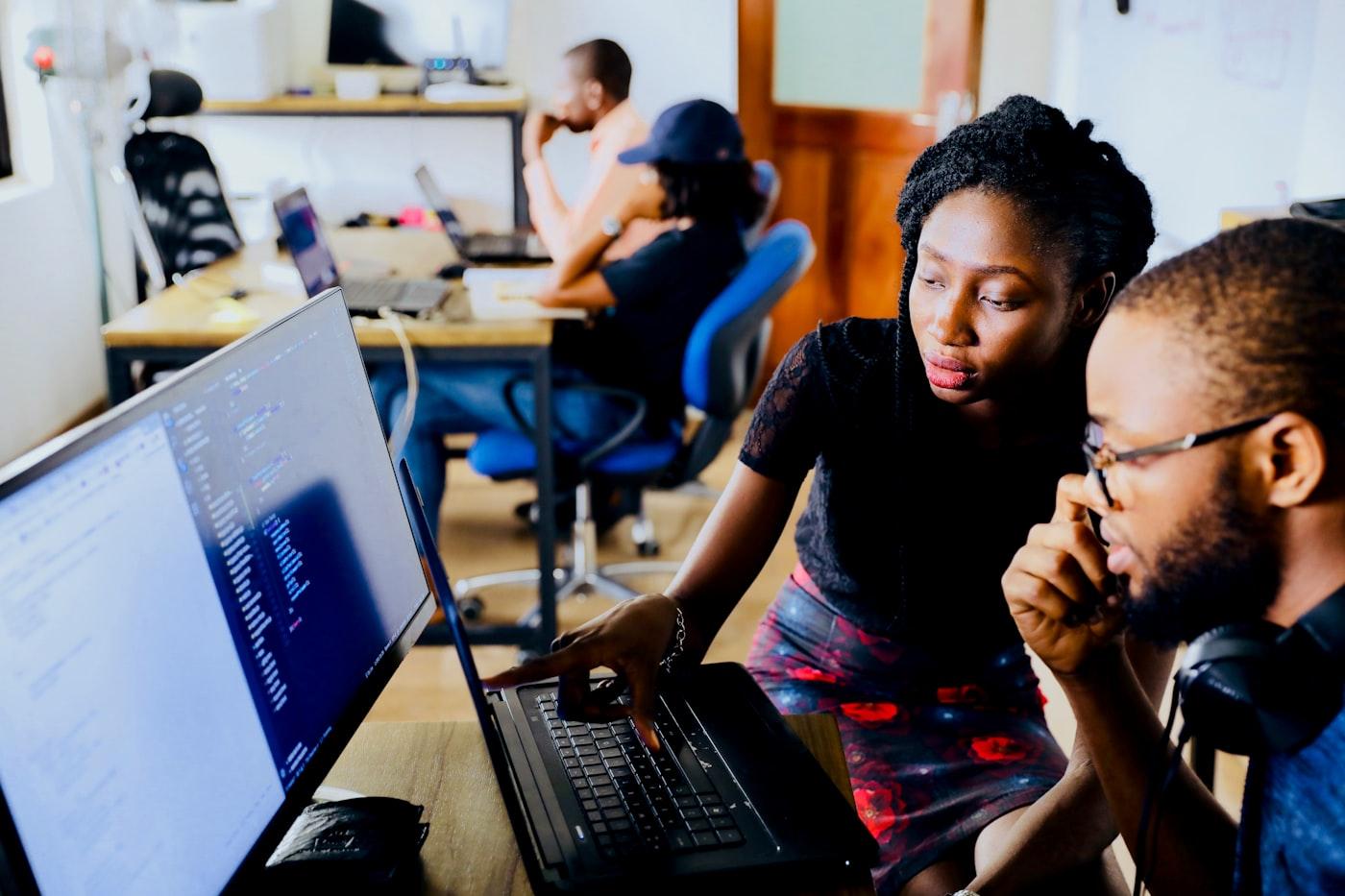 Two colleagues reviewing work together on a laptop